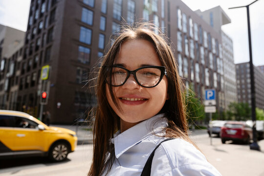 A confident businesswoman smiles on a city street near a taxi