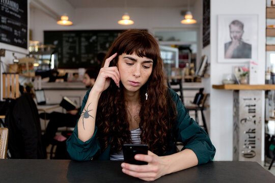 Young woman using cell phone in a cafe