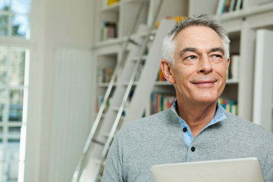 Smiling man holding tablet in residential house in Berlin