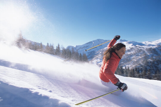 Smiling skier in red jacket skiing downhill on snowy mountain