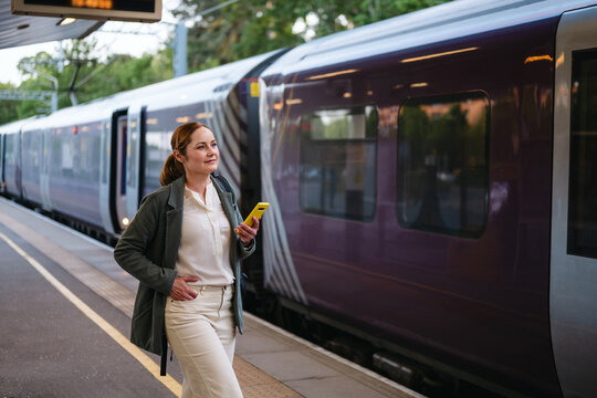 Businesswoman with smartphone waiting at train station