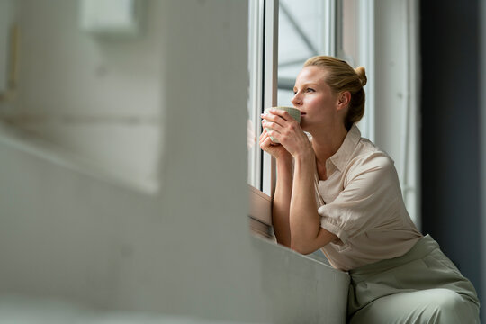 Young businesswoman with cup of coffee looking out of window