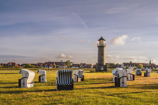 Germany, Lower Saxony, Juist, Hooded beach chairs in front of Memmertfeuer lighthouse