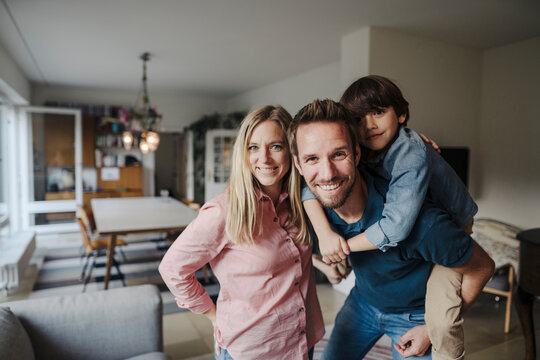 Happy family standing in livingroom, smiling at camera