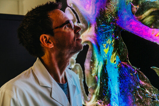Scientist examining projection of human brain with nerve fiber while standing at laboratory