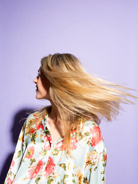 Blonde woman tossing hair against a purple background