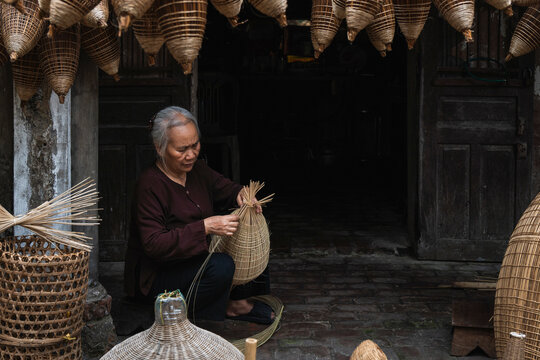 Artisan weaving bamboo fish trap outdoors in Hanoi Vietnam