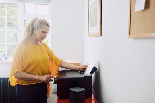 A woman presses a button on a printer in her London home office