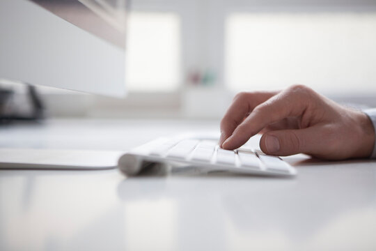 Man's hand typing on keyboard of computer