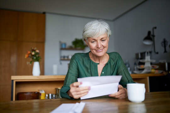Senior woman reading letter while sitting at home