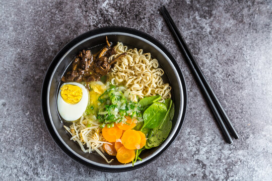 Bowl of ramen soup with spinach, carrot, boiled egg, bamboo sprouts and mushrooms