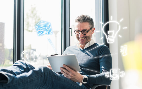 Man sitting in office, using digital tablet to remote-control his smart home