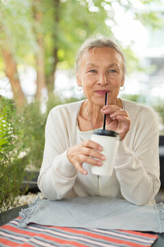 Smiling senior woman at an outdoor cafe looking sideways