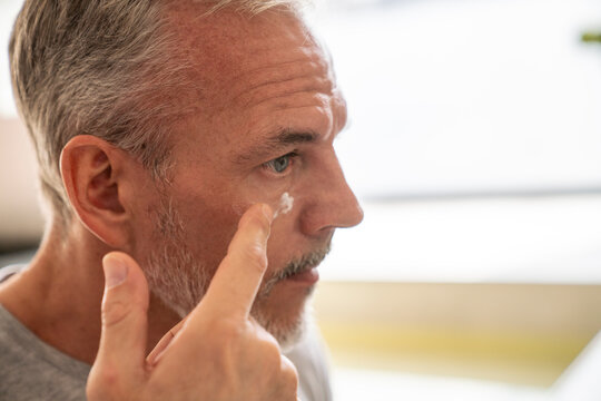 Man applying cream on face in bathroom