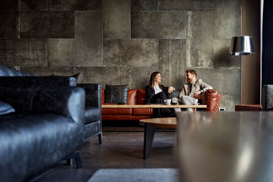 Businessman and businesswoman sitting on couch in hotel lobby