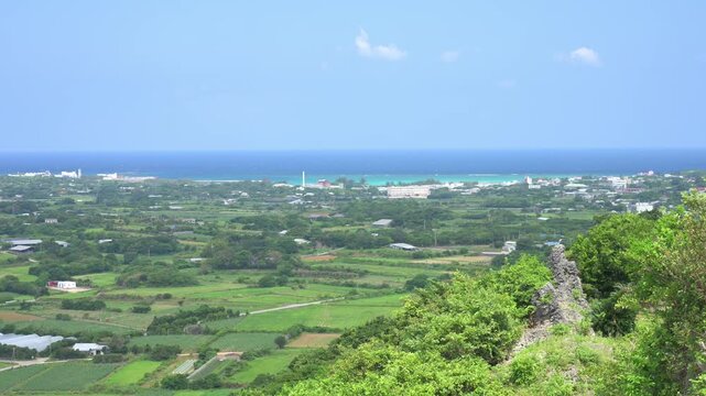 青空の下に広がるのどかな島の田園風景と遠くに広がる青い海