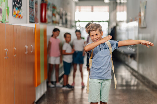 Schoolboy dabbing in hallway with friends