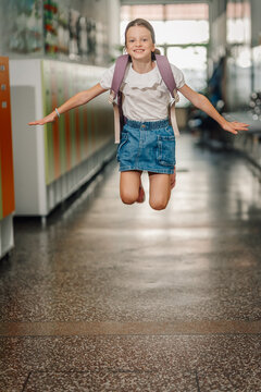 Happy student girl jumping in school hallway