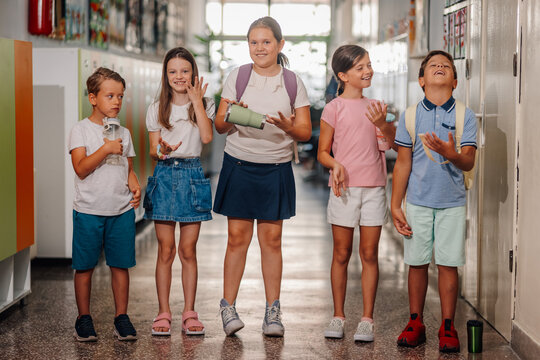 Group of children walking school hallway with backpacks