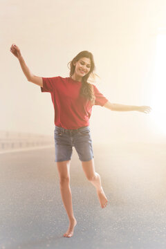 Young woman dancing joyfully on the road.