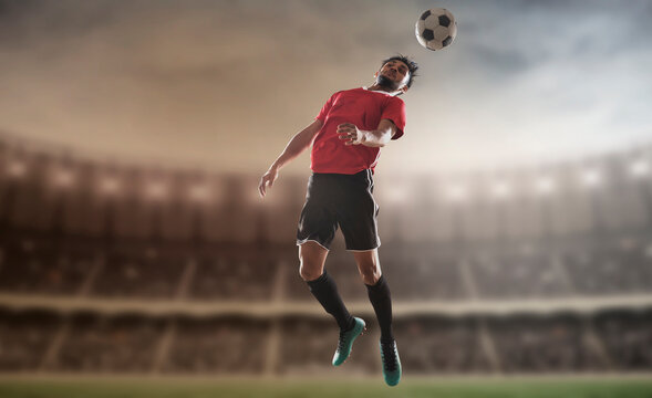 Footballer heading the football in the stadium.