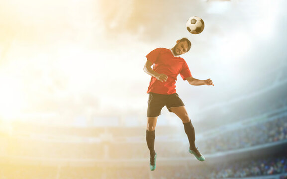 Footballer heading the football in the stadium.