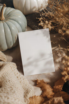 Cozy autumn flat lay top view table setting mockup featuring a blank vertical 5x7 card template with a blue pumpkin and fall leaves.