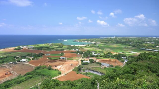 青空の下に広がるのどかな島の田園風景と遠くに広がる青い海