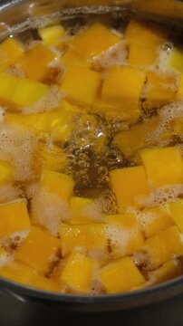Vertical video. Cooking pumpkin puree soup. Pumpkin pieces in a boiling pot of water