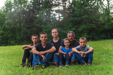 Fototapeta premium Happy family of parents and four sons smiling together outdoors on a green meadow in nature