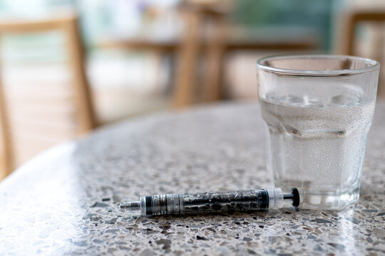 Insulin pen glass of water medical device injection pen table top close up bistro table natural light empty space diabetes care treatment healthcare medicine sterile transparent glass liquid copy