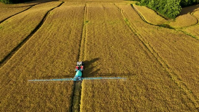 Wide Aerial View of Tractor Spraying Patchwork Farm Fields