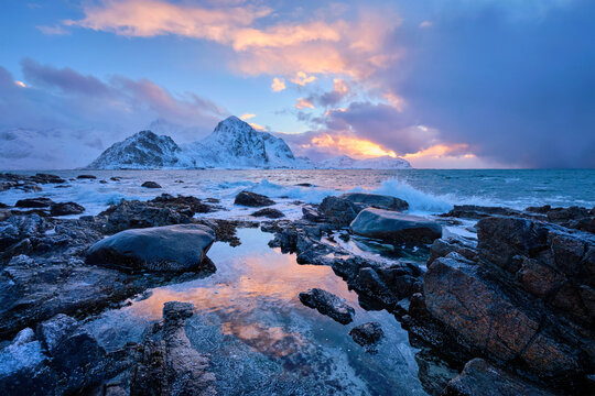 Beach of Norwegian sea on rocky coast in fjord at sunset in winter. Vareid beach, Lofoten islands, Norway