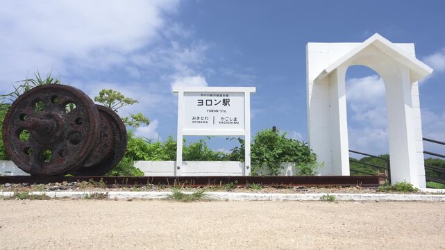 与論島の観光名所「ヨロン駅」の駅名標と線路・車輪のモニュメント