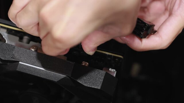 A close-up of a person's hands using a tool to work on hardware components inside an open desktop computer case.