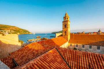 Fototapeta premium Golden hour panorama of Dubrovnik's historic fortifications and old port at dusk, featuring sunlight on ancient stone walls and Mediterranean architecture in Croatia