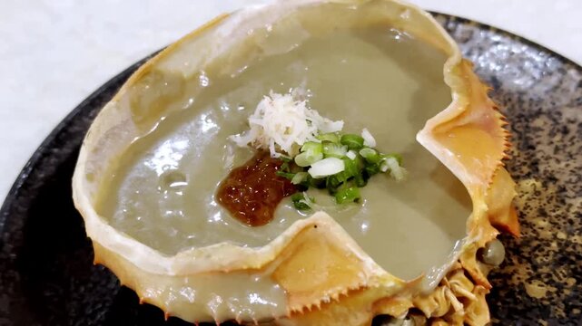 Close-up of a crab shell filled with rich and creamy crab tomalley, beautifully presented as a premium seafood delicacy in Japanese cuisine.