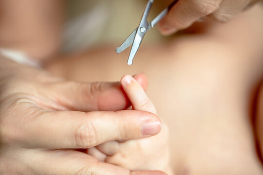 Mother gently holding hand of newborn baby showing trust and bonding during nail care