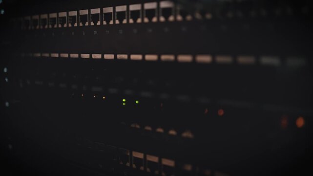 A dramatic close-up of server rack units in a dark data center with small orange LED indicator lights glowing in rows.