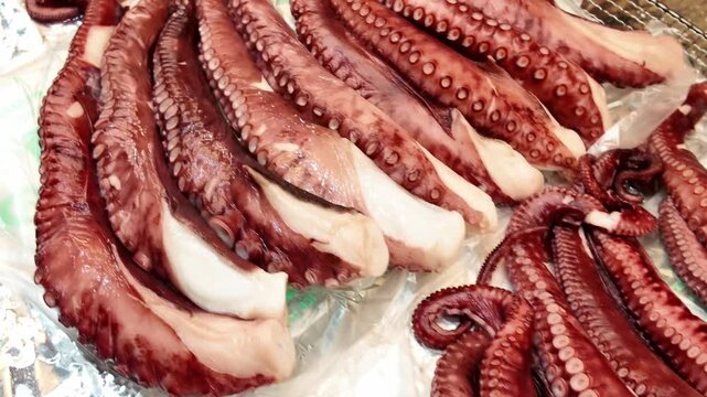 Fresh octopus tentacles and whole squid prepared on foil at a seafood market stall