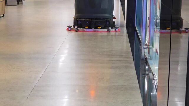 Automatic floor scrubber machine cleaning polished tiled surface of public building corridor, ensuring hygiene and maintenance with efficient mechanization