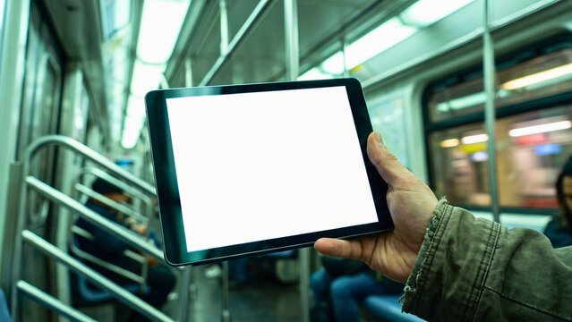 Hand holding tablet edge inside subway train, commuter app advertising mockup, marketing display with copy space