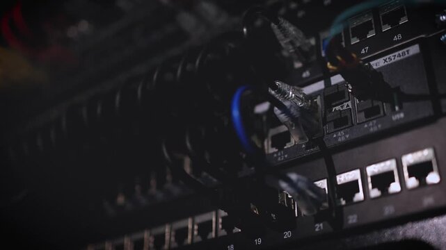A close-up of server rack components and network connections in a dark data center with visible cable management.
