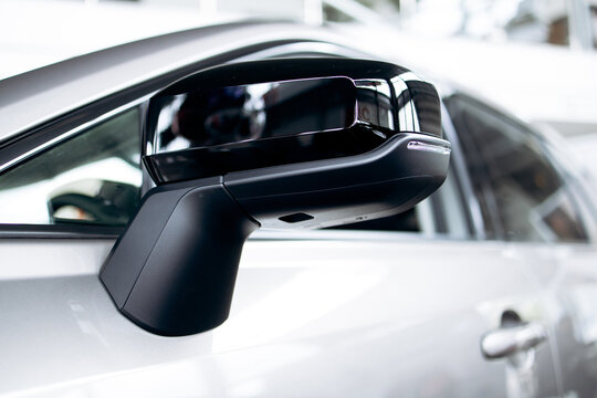 Close up view of a contemporary car's wing mirror, featuring a sleek black design and built-in led turn indicator light
