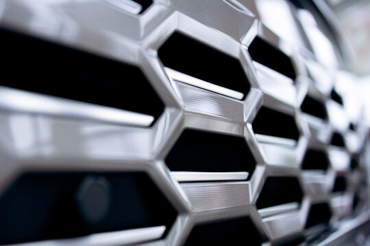 Car grill closeup highlights the intricate silver honeycomb design, representing automotive engineering and luxury vehicle aesthetics