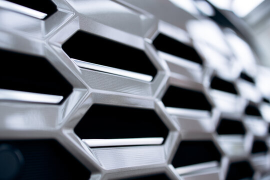 Automobile grille detail showing hexagonal abstract design and metallic texture. Automotive engineering and modern technology concept