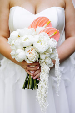 Bride carrying a beautiful floral bouquet with white peonies, garden roses, anthuriums, and amaranth hanging down