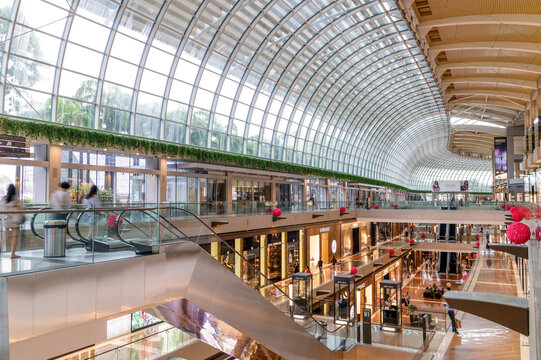 Interior view of The Shoppes at Marina Bay Sands in Singapore, iconic curved glass roof, luxury retail stores, escalators, spacious modern shopping mall architecture