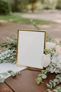 Vertical 8x10 gold metal frame mockup featuring a blank white paper sign template with eucalyptus leaves and white roses.