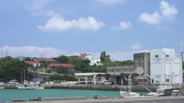 エメラルドグリーンの海に漁船が停泊するのどかな港の風景